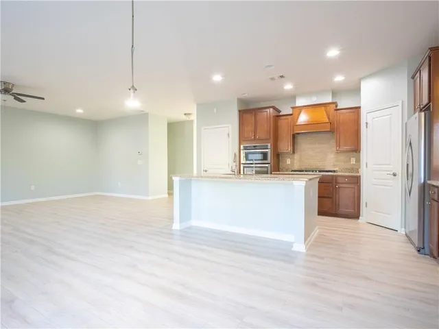 a kitchen with stainless steel appliances kitchen island granite countertop a refrigerator a sink and a stove