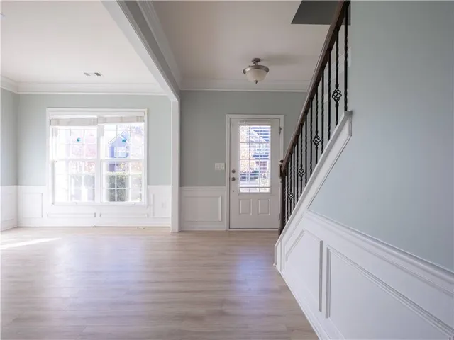 a view of an empty room with wooden floor and fan