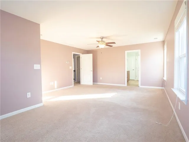 an empty room with ceiling fan and windows