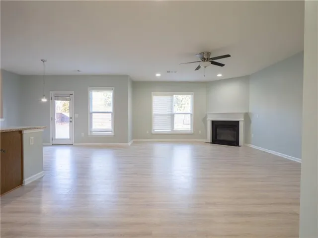 an empty room with wooden floor fireplace and windows