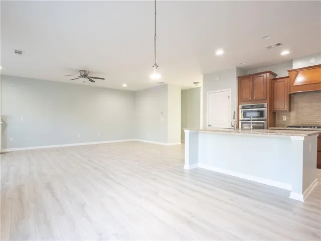 a view of a kitchen with kitchen island a sink wooden floor and stainless steel appliances