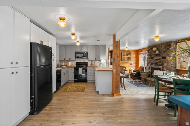 2189 Samak Park Loop, Unit 43 Kamas, UT 84036 - Photo 48 of 48 Kitchen featuring open floor plan, a fireplace, black appliances, light wood-style flooring, and gray cabinetry
