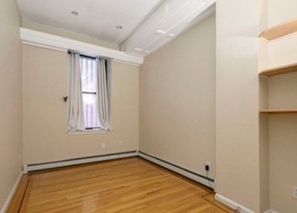 a view of an empty room with wooden floor and closet