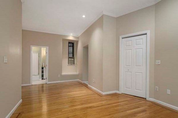 a view of an empty room with wooden floor and closet