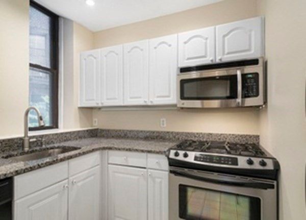 a kitchen with granite countertop a stove top oven microwave and cabinets