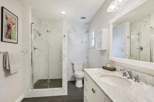 a bathroom with a granite countertop sink a toilet a shower and a mirror