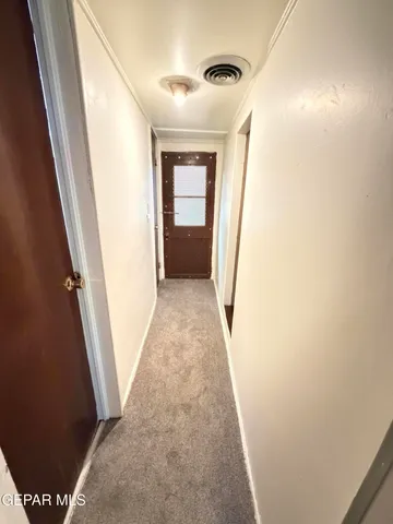 a view of a hallway with wooden floor and a bathroom