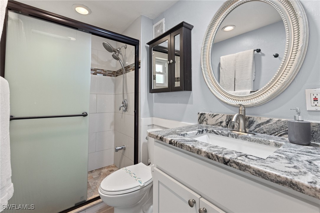 5216 Rutland Court Cape Coral, FL 33904 - Photo 26 of 47 a bathroom with a granite countertop sink toilet a mirror and shower