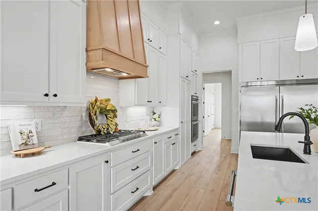 a kitchen with stainless steel appliances granite countertop a sink a stove and a refrigerator