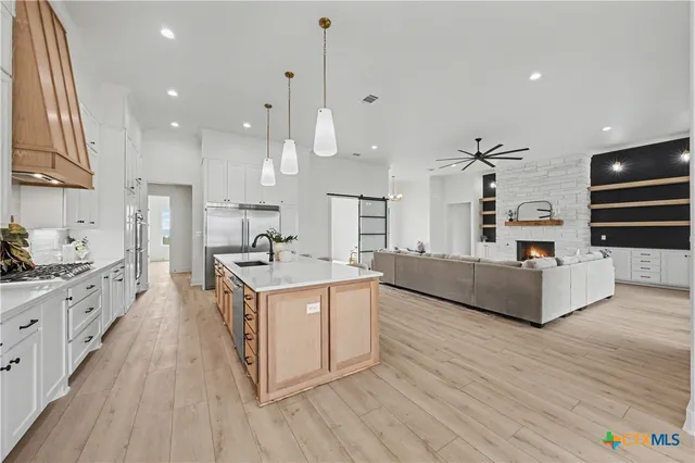 a large kitchen with stainless steel appliances kitchen island granite countertop a stove a sink a refrigerator and a dining table with wooden floor