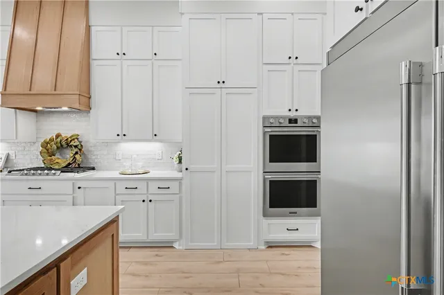 a kitchen with stainless steel appliances white cabinets and a refrigerator
