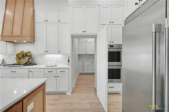 a kitchen with white cabinets and refrigerator