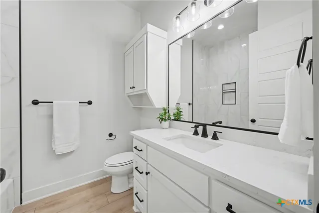 a bathroom with a sink a toilet and shower