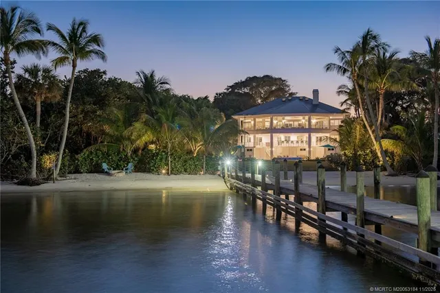 a view of a patio with a table and chairs under an umbrella with palm trees