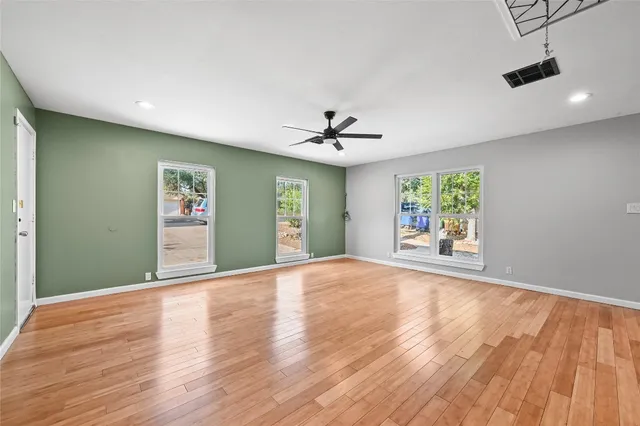 a view of an empty room with a window and wooden floor