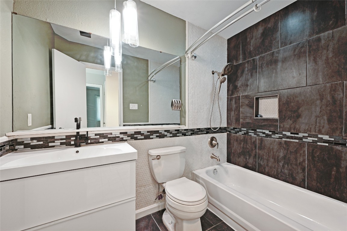 5304 China Berry Road Austin, TX 78744 - Photo 19 of 24 a bathroom with a sink a toilet a mirror a bathtub and shower
