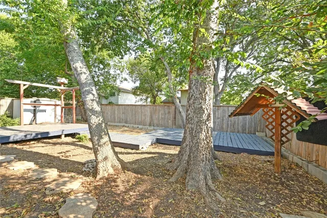 a view of backyard with wooden fence and large trees