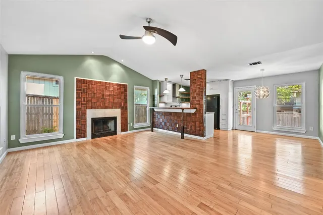 a view of an empty room with a fireplace and wooden floor