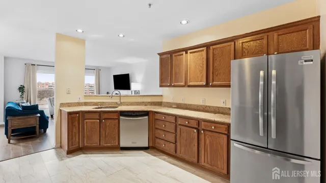 a kitchen with stainless steel appliances granite countertop a refrigerator a stove and a sink with wooden floor
