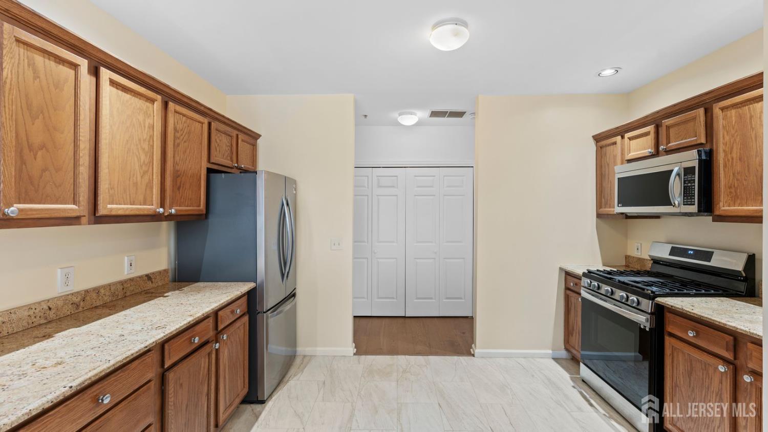 344 The Promenade Edgewater, NJ 07020 - Photo 15 of 44 a kitchen with stainless steel appliances granite countertop a refrigerator a stove and a sink with wooden floor