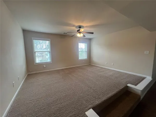 an empty room with windows and ceiling fan