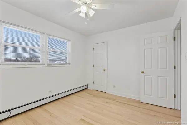 a view of empty room with wooden floor and fan