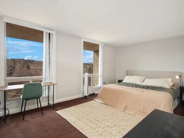 a bedroom with a bed a chair and next to a window