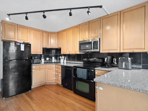 a kitchen with stainless steel appliances granite countertop a refrigerator a stove a sink and a microwave