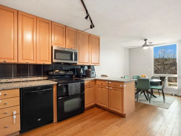 a kitchen with stainless steel appliances granite countertop wooden floors and wooden cabinets