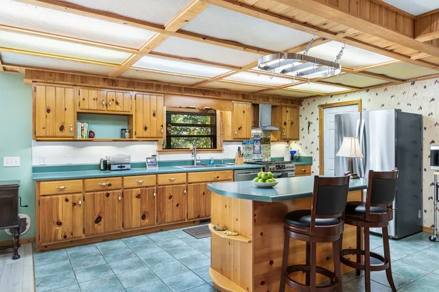 a kitchen with stainless steel appliances granite countertop a table chairs and a refrigerator