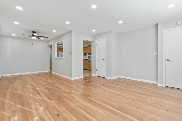 a view of an empty room with wooden floor and a bathroom