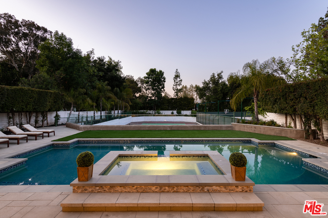 a view of swimming pool with outdoor seating and trees in the background