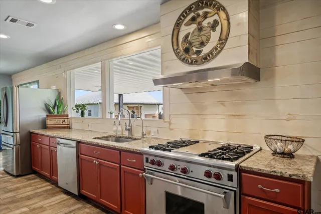 a kitchen with stainless steel appliances a refrigerator and a potted plant