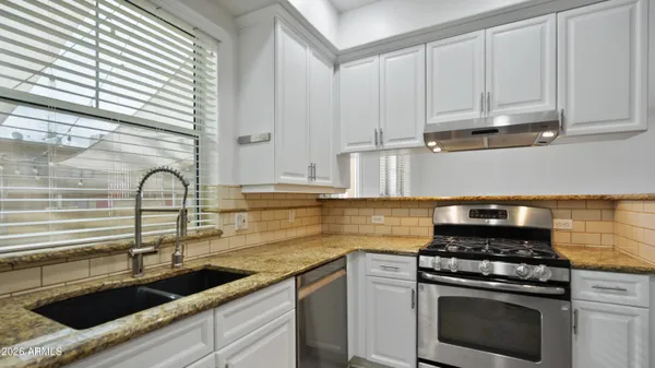 a kitchen with stainless steel appliances granite countertop a sink a stove a refrigerator and island