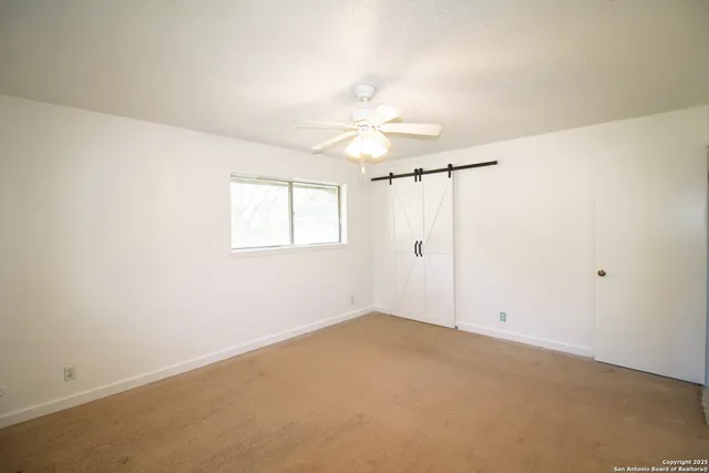 an empty room with a window and a ceiling fan
