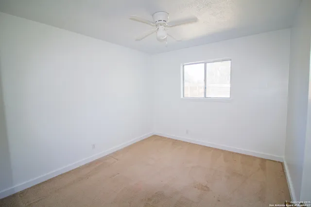an empty room with windows and chandelier fan
