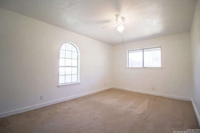 an empty room with a window and ceiling fan