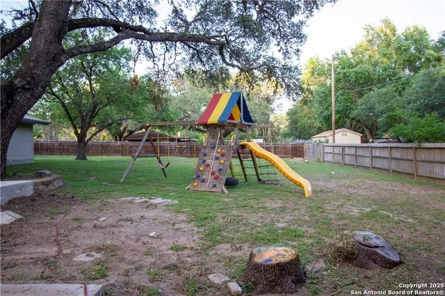 a view of backyard with wooden fence and a large tree