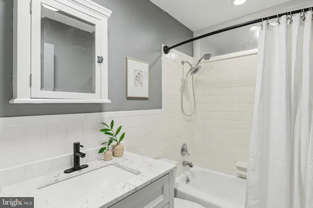 a bathroom with a tub shower vanity and a sink