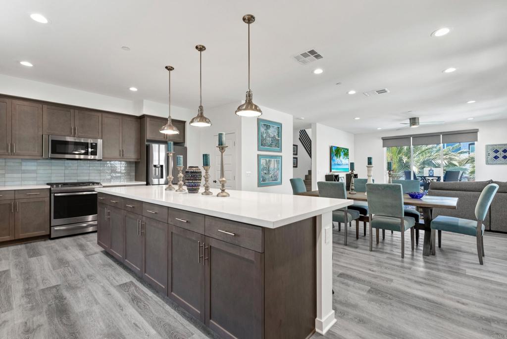 a kitchen with stainless steel appliances kitchen island granite countertop a sink a stove and a wooden floors
