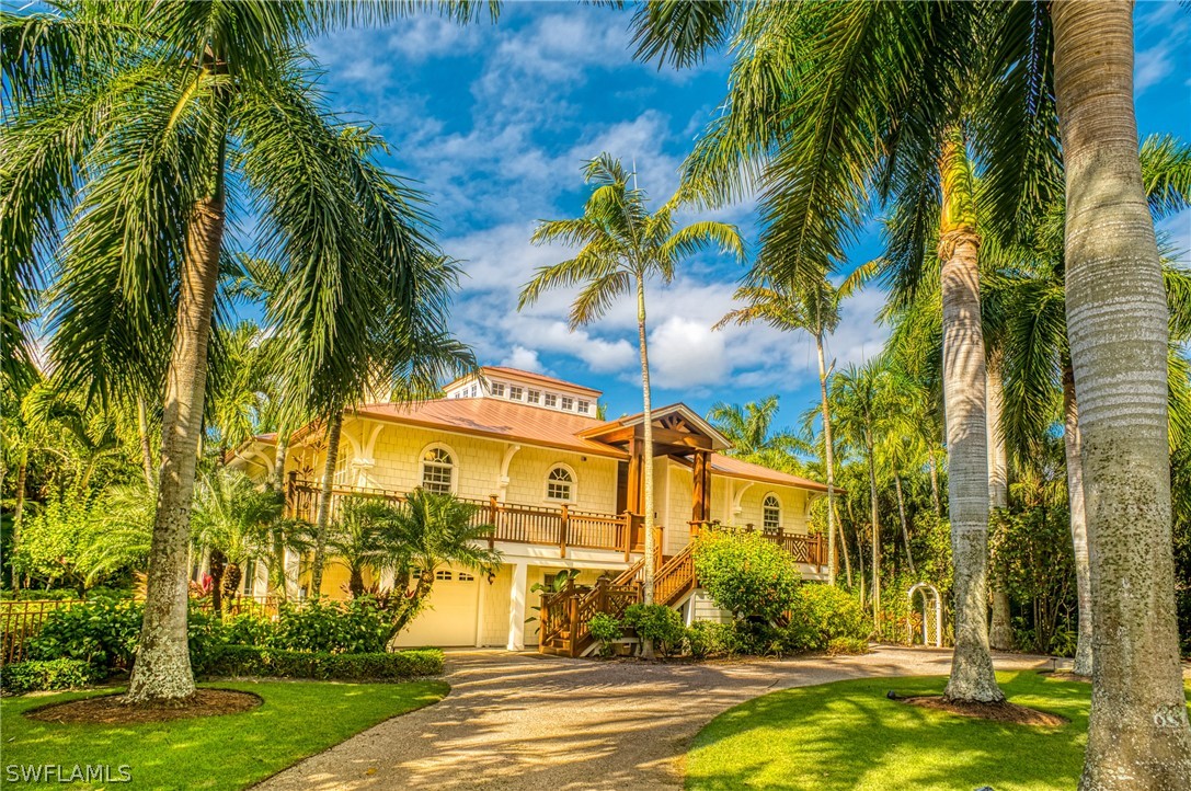 a view of a white house with a big yard and palm trees