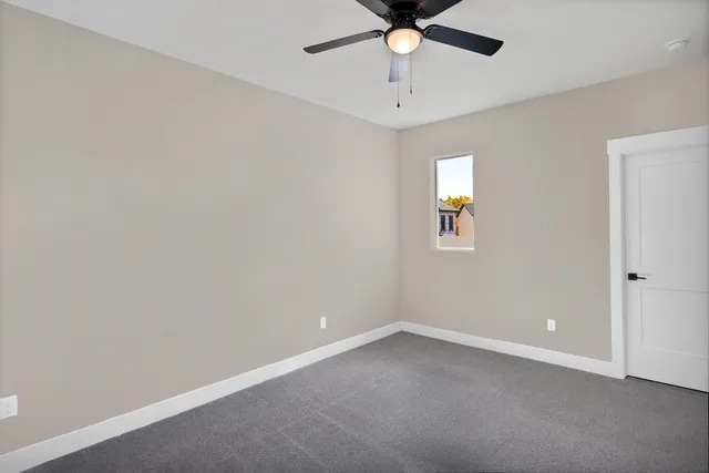 an empty room with a window and a fan