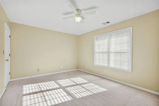 an empty room with a chandelier fan and a window