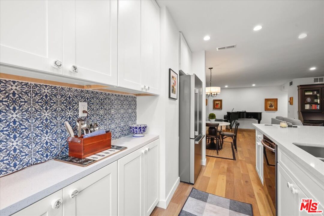 7250 Franklin Avenue, Unit 101 Los Angeles, CA 90046 - Photo 11 of 33 a kitchen with stainless steel appliances granite countertop a refrigerator a stove and white cabinets with wooden floor