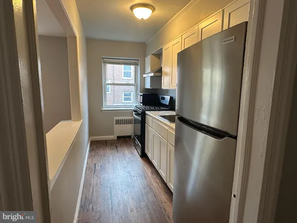 a kitchen with white cabinets and refrigerator