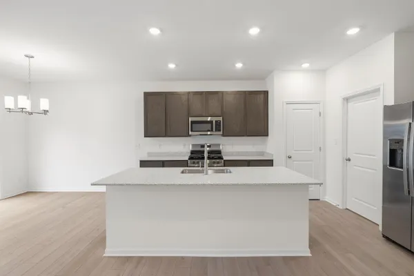 a kitchen with stainless steel appliances granite countertop a sink a stove a chimney a refrigerator and cabinets