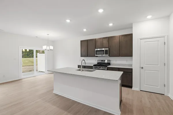 a large kitchen with stainless steel appliances a large counter top and wooden floors
