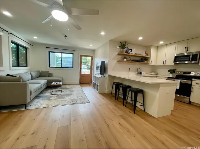 a living room with stainless steel appliances granite countertop furniture wooden floor and a view of kitchen