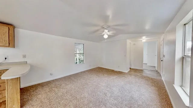 an empty room with windows and fan