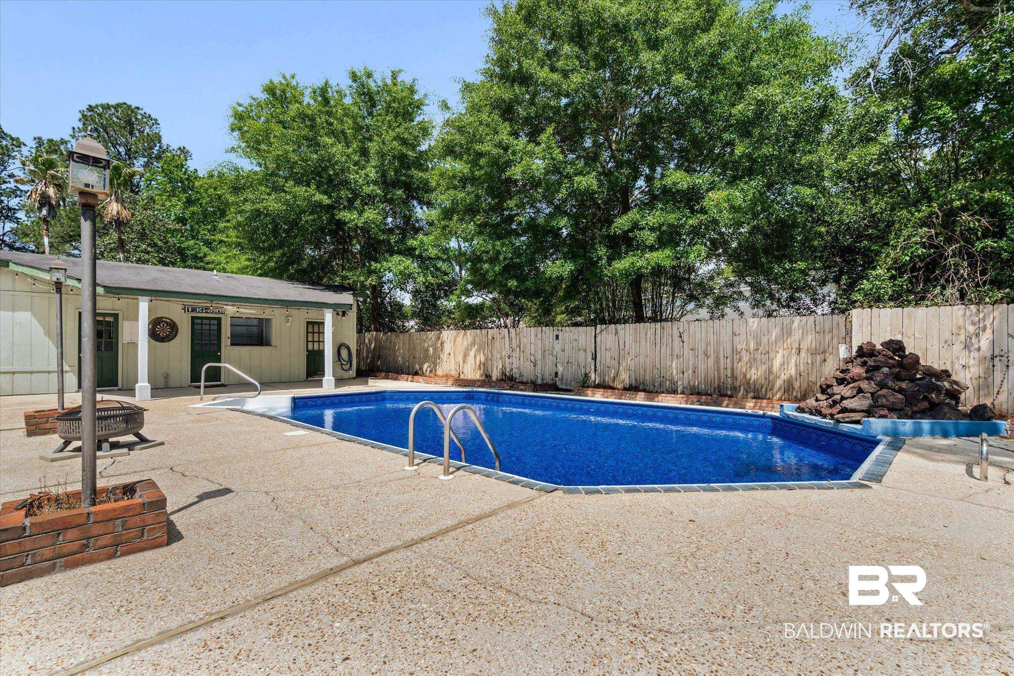 3724 Claridge Road South Mobile, AL 36608 - Photo 3 of 42 View of swimming pool with a fenced backyard, a fire pit, patio surround, and an outbuilding